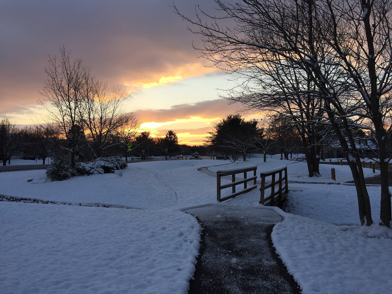 Snowy walking path beneath a colorful sunrise