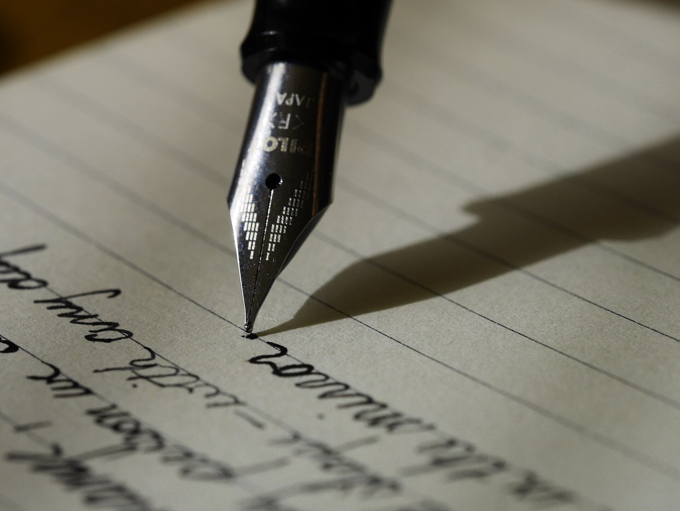 Hand writing thoughtfully in a notebook beside soft light